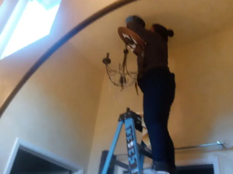Electrician installing a chandelier in a Garfield residence